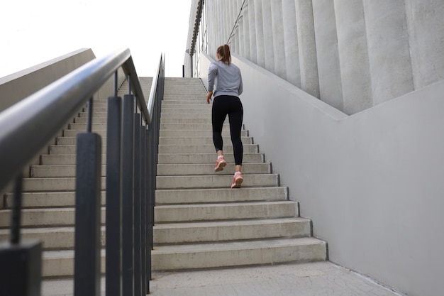 Vista posteriore dell'atleta corridore in esecuzione sulle scale. La forma fisica della donna è fare jogging all'aperto.
