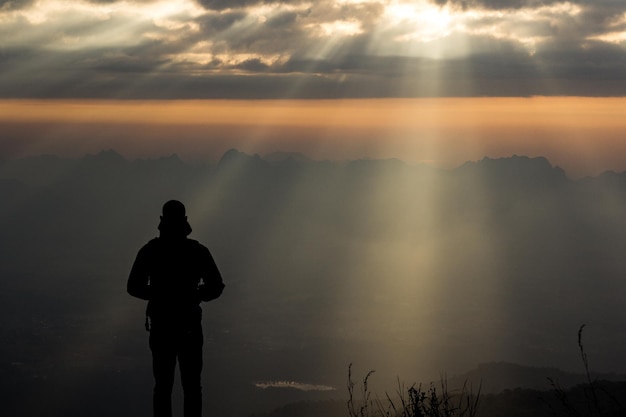 Vista posteriore dell'uomo a silhouette in piedi sulla montagna contro il cielo durante il tramonto