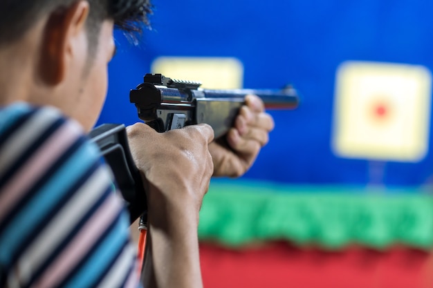 Vista posteriore dell&#39;uomo con la sua pistola sul tiro al bersaglio in pratica Shooting Range, sport e Soldie