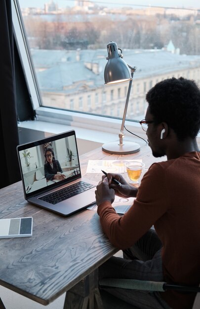 Vista posteriore dell'uomo d'affari che parla con il suo collega sul laptop durante la riunione online