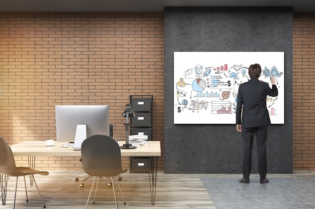 Vista posteriore dell'uomo d'affari in abito nero che disegna un poster motivazionale nell'ufficio del CEO