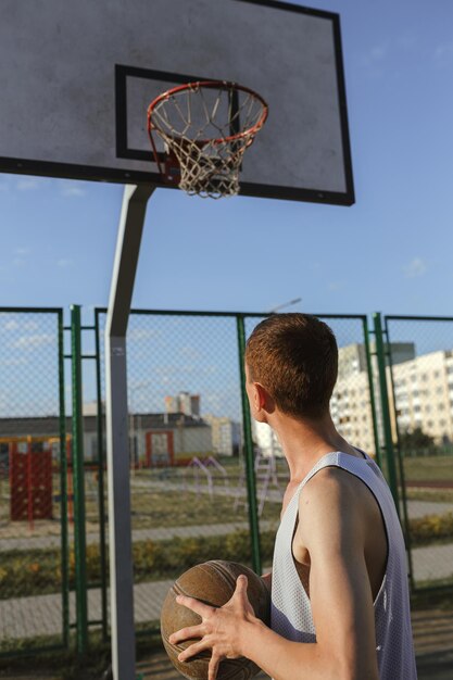 Vista posteriore dell'uomo sportivo che gioca a basket sul campo urbano in estate