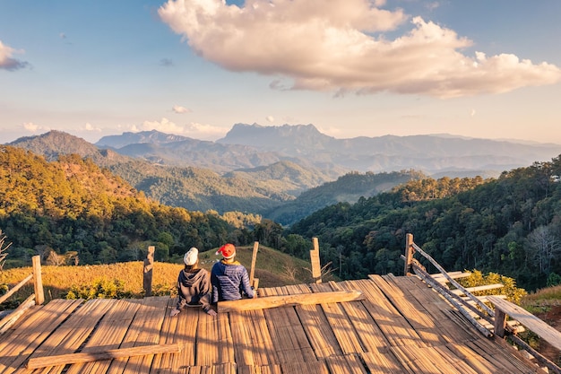 Vista posteriore della coppia asiatica godendo la vista sulle montagne sul balcone di legno la sera al punto di vista della campagna Hadubi Wiang Haeng Chiang Mai Thailandia