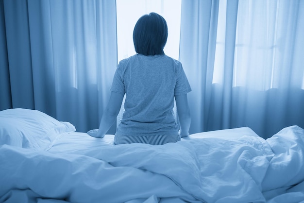 Vista posteriore della donna che si sente depressa e seduta sul letto