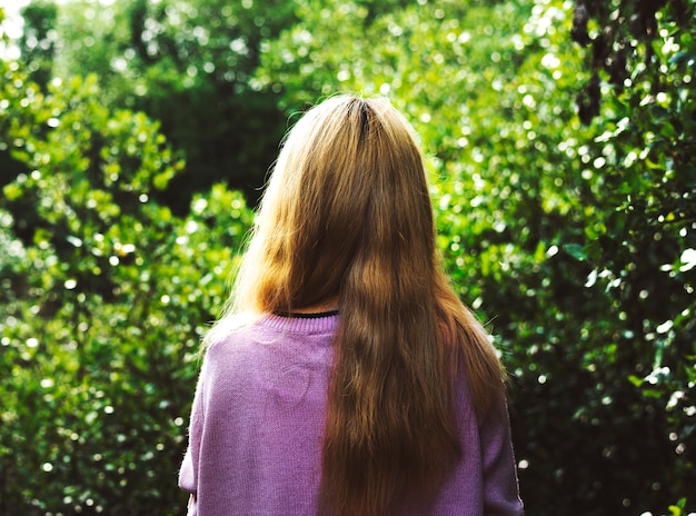 Vista posteriore della donna con i capelli lunghi in giardino