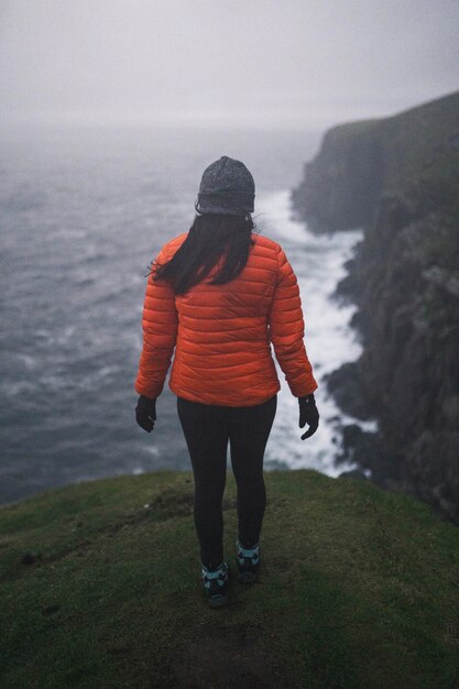 Vista posteriore della donna in piedi vicino alla scogliera a Isola di Skye, Scotland