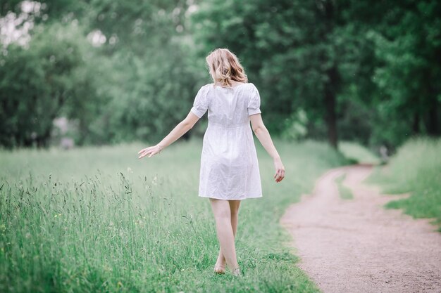 Vista posteriore della donna incinta che cammina a piedi nudi sull'erba