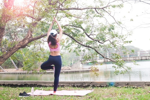 Vista posteriore della donna sottile in abbigliamento fitness facendo yoga posa nel parco, bellezza e salute