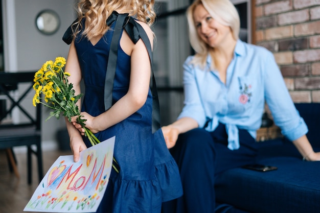 Vista posteriore della figlia adorabile che si nasconde dietro la sorpresa per sua madre