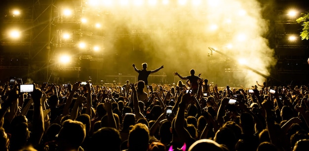 Vista posteriore della folla di persone davanti al palco che filma il concerto di musica con i telefoni cellulari Spazio di copia