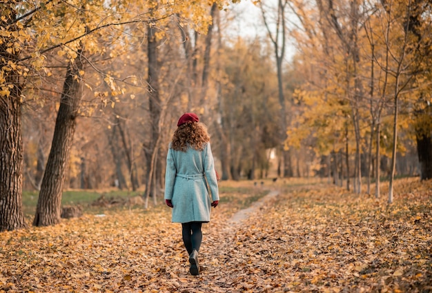 Vista posteriore della giovane donna elegante in cappotto casual grigio in autunno.