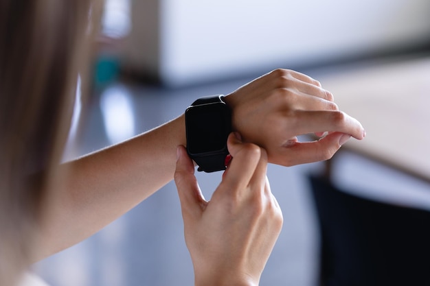 Vista posteriore della sezione centrale di una donna d'affari che lavora in un ufficio moderno, con uno smartwatch al polso sinistro.