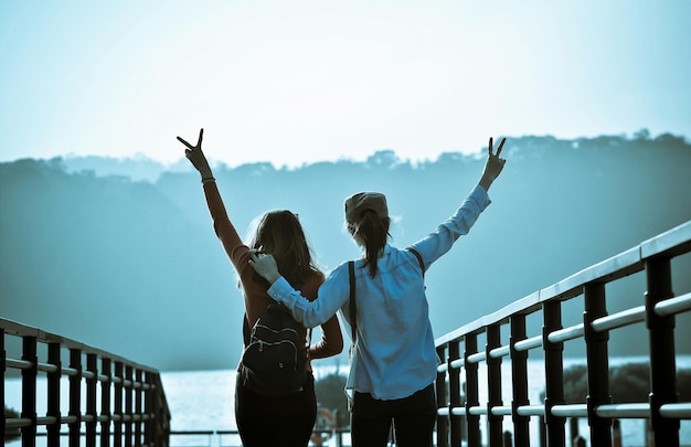 Vista posteriore di amici che fanno gesti mentre camminano sul ponte