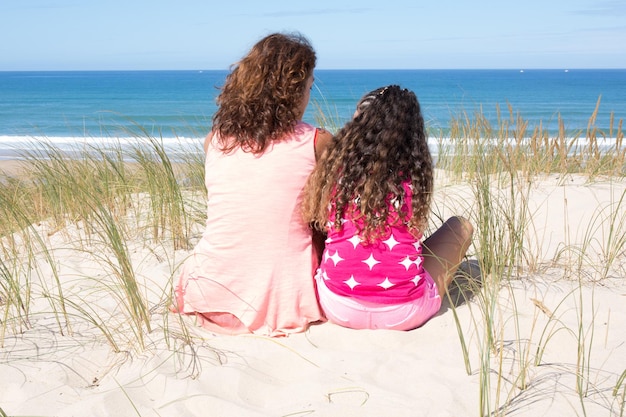 Vista posteriore di due ragazze in vacanza in spiaggia