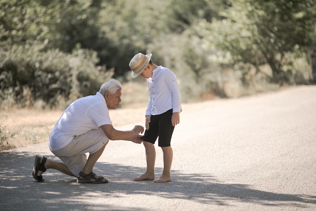 Vista posteriore di nonno e nipote con cappello che cammina sulla natura