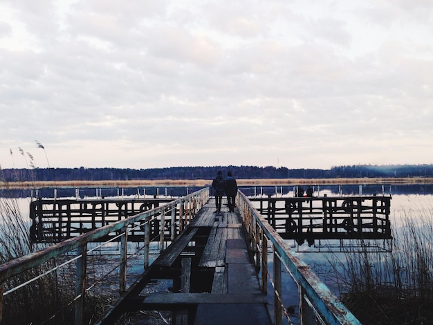Vista posteriore di persone che camminano sul molo sul fiume