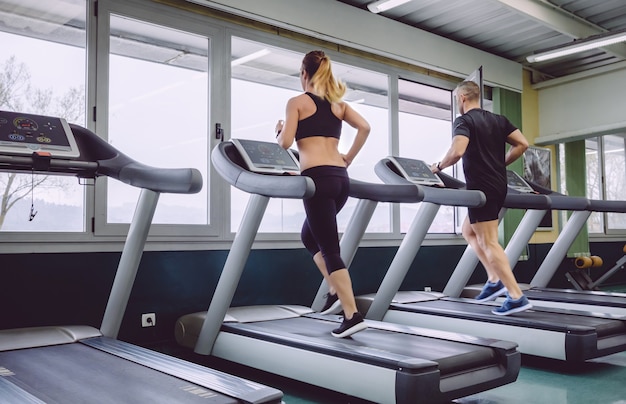 Vista posteriore di persone che corrono sul tapis roulant in una sessione di allenamento nel centro fitness