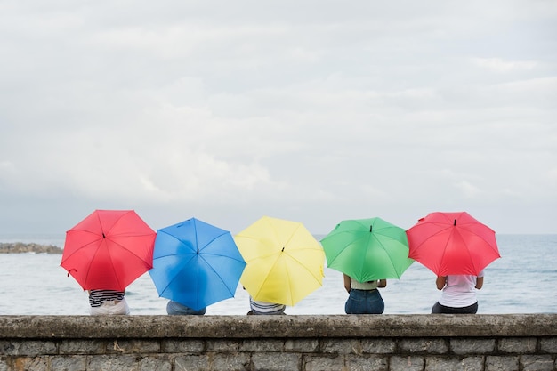 Vista posteriore di persone che guardano il mare con ombrelloni