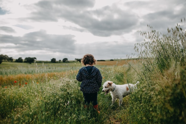 Vista posteriore di un bambino e di un cane in piedi sul campo