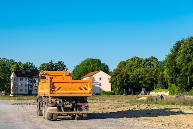 Vista posteriore di un camion carico arancione su un cantiere vuoto