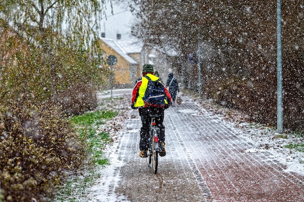 Vista posteriore di un ciclista che guida su un marciapiede lastricato durante una nevicata