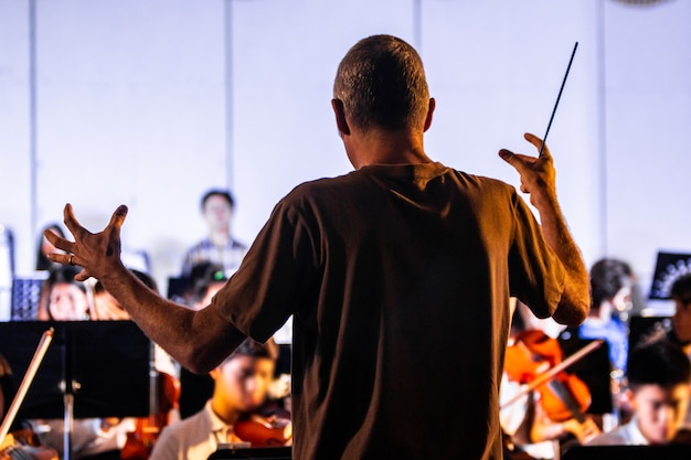 Vista posteriore di un conduttore maschile che dirige la sua band in una scuola locale