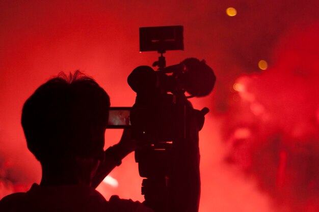 Vista posteriore di un fotografo di silhouette che registra un video di notte