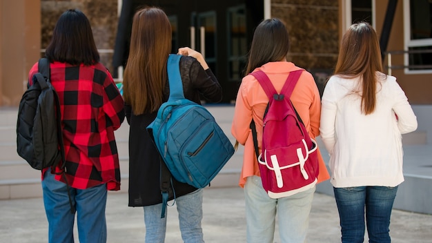Vista posteriore di un gruppo di quattro giovani studenti universitari attraenti ragazze asiatiche che camminano insieme nel campus universitario. Concetto per l'istruzione, l'amicizia e la vita degli studenti universitari.
