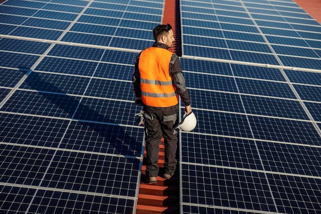 Vista posteriore di un lavoratore alla ricerca di pannelli solari da mantenere