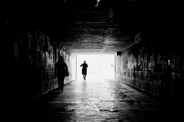 Vista posteriore di un uomo a silhouette che cammina sul sentiero in un tunnel