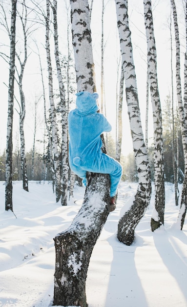 Vista posteriore di un uomo adulto che si arrampica su un albero nella foresta durante l'inverno