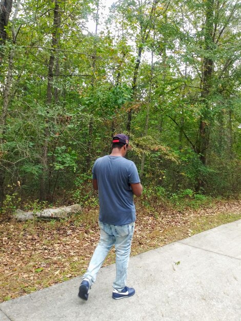 Vista posteriore di un uomo che cammina su un sentiero nella foresta