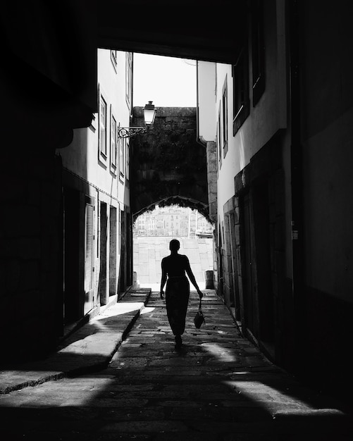 Vista posteriore di un uomo che cammina sul vicolo tra gli edifici della città
