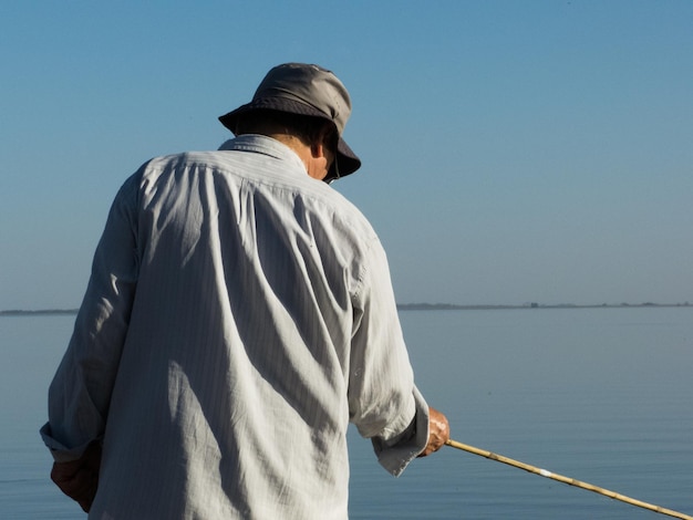 Vista posteriore di un uomo che pesca in mare