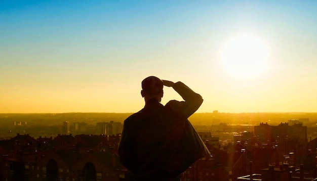 Vista posteriore di un uomo che protegge gli occhi dal cielo durante il tramonto