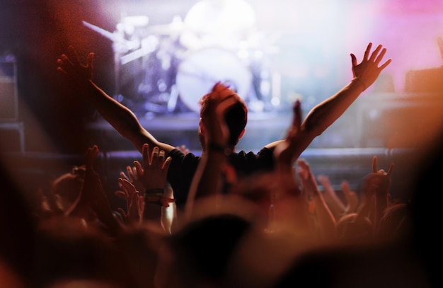 Vista posteriore di un uomo con le braccia tese al concerto