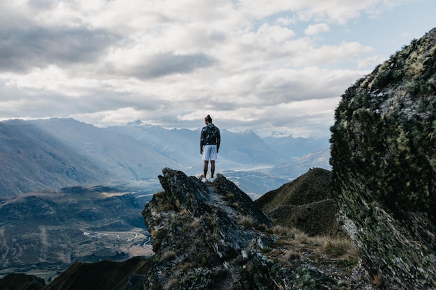 Vista posteriore di un uomo in piedi su una montagna contro il cielo