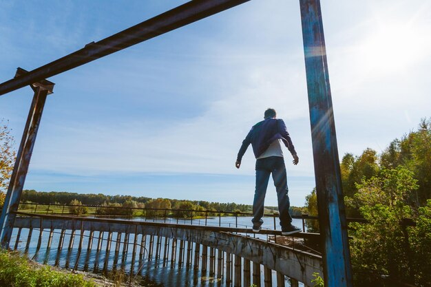 Vista posteriore di un uomo in piedi su una ringhiera contro il cielo