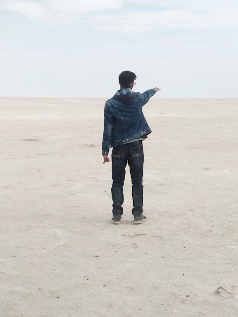 Vista posteriore di un uomo in piedi sulla sabbia