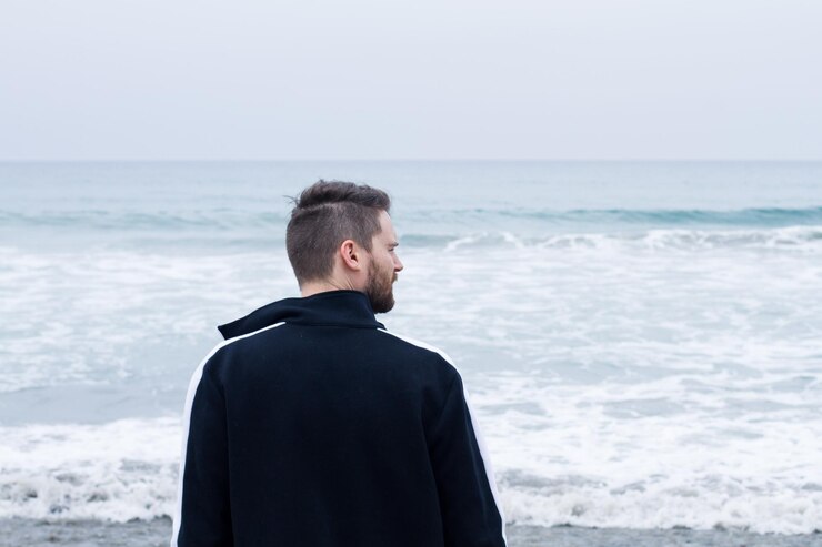 Foto vista posteriore di un uomo sulla spiaggia contro il cielo