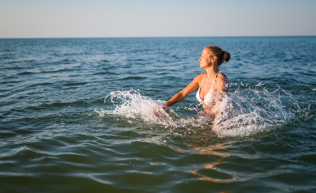Vista posteriore di una bella giovane donna che nuota in mare in una calda giornata estiva soleggiata. Il concetto di riposo e godimento dei viaggi turistici. Copyspace