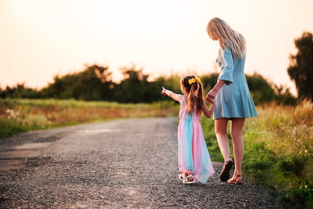 Vista posteriore di una bella madre sottile che cammina per mano