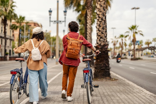 Vista posteriore di una coppia che spinge le biciclette per strada e cammina