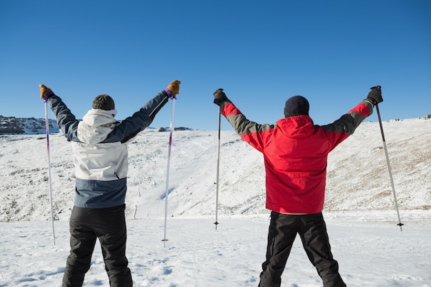 Vista posteriore di una coppia con bastoncini da sci sulla neve