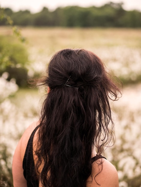 Vista posteriore di una donna bruna in piedi sul campo