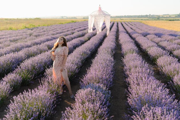 Vista posteriore di una donna che cammina lungo le file di un campo di lavanda