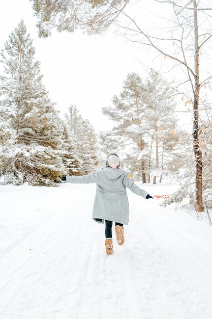 Vista posteriore di una donna che cammina sugli alberi coperti di neve