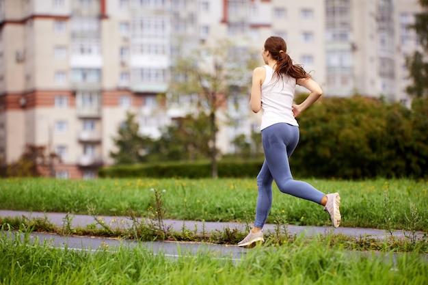 Vista posteriore di una donna che corre nel parco durante il giorno