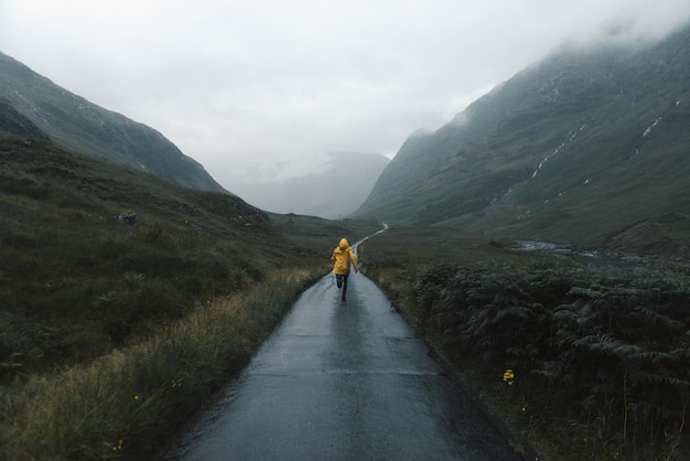Vista posteriore di una donna che corre su una strada di campagna nelle Highlands scozzesi