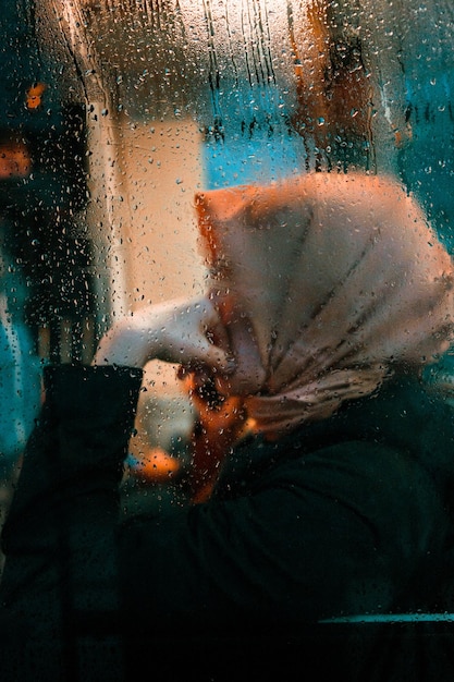 Vista posteriore di una donna che guarda attraverso la finestra